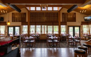 Spacious dining room at Terrazza Greenfield with chandeliers, set tables, and Country Club of Greenfield golf champion boards