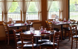 Set dining tables near curtained windows overlooking the deck railing at Terrazza Greenfield