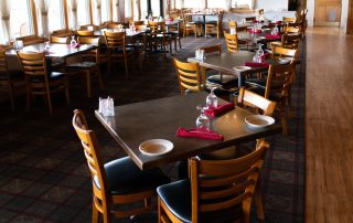 Interior dining room at Terrazza Greenfield with set tables, wooden chairs, and large windows