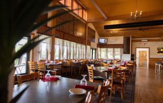 "Elegant indoor dining room at Terrazza Greenfield with set tables, chandeliers, and large windows overlooking the golf course