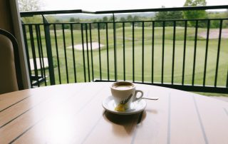 Espresso on the outdoor deck table with a wide view of the golf course green at Terrazza Greenfield