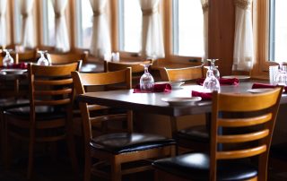 Set tables with wine glasses and red napkins in Terrazza Greenfield's dining room near large windows