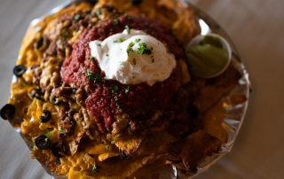 Loaded nachos with melted cheese, salsa, sour cream, black olives, and guacamole served at Terrazza Greenfield