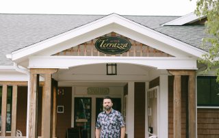 Man standing in front of Terrazza Italian Restaurant entrance with sign and covered porch at Terrazza Greenfield