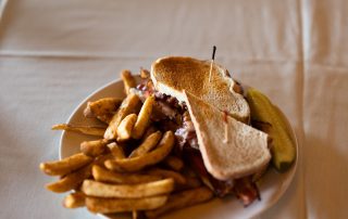 Toasted club sandwich with bacon served with fries and a pickle at Terrazza Greenfield