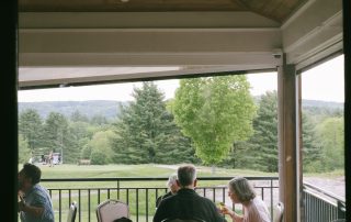 Guests enjoying a meal on the covered outdoor deck at Terrazza Greenfield with golf course and mountain views